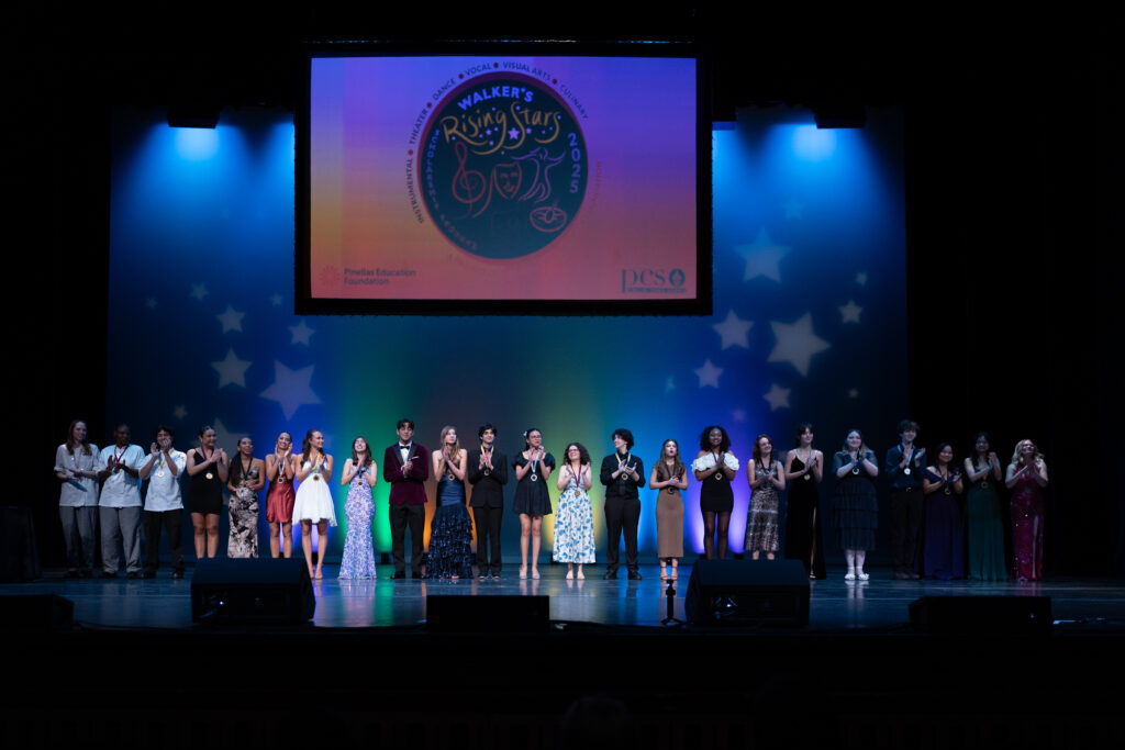 Group of students on stage clapping at Walker's Rising Stars